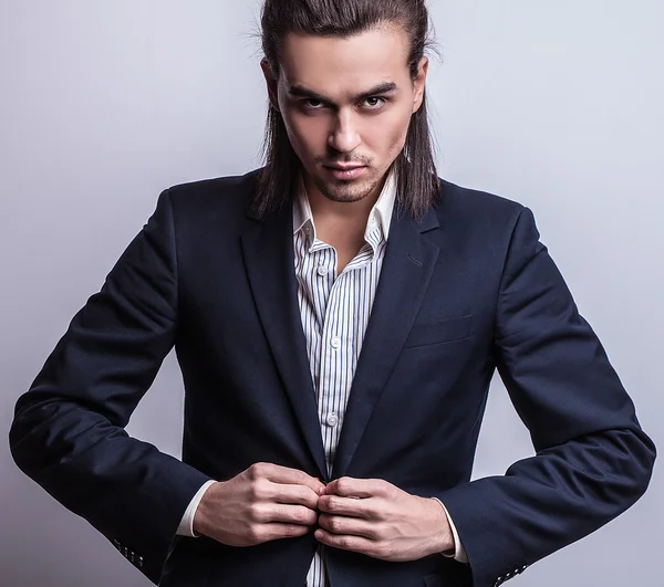 Elegante jonge knappe langharige man in kostuum. Studio mode portret. — Stockfoto