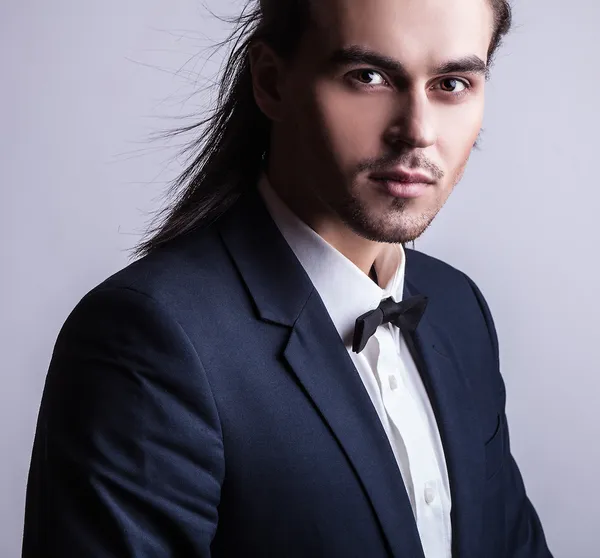 Elegante jonge knappe langharige man in kostuum. Studio mode portret. — Stockfoto