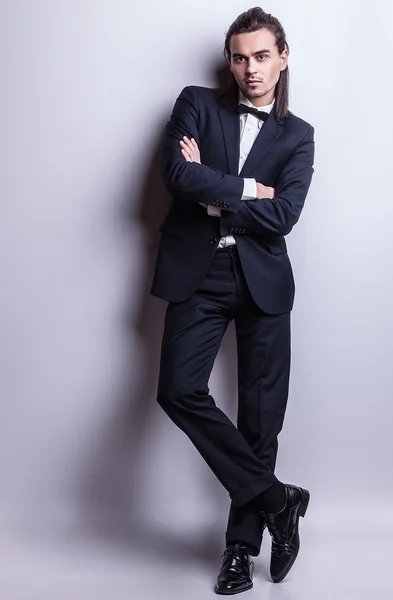 Elegantní mladý pohledný dlouhovlasý muž v kostýmu. portrét módní Studio. — Stock fotografie