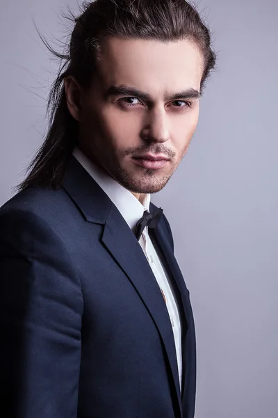 Elegante jonge knappe langharige man in kostuum. Studio mode portret. — Stockfoto