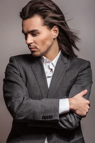 Elegante giovane uomo dai capelli lunghi in costume. Studio ritratto di moda . — Foto Stock