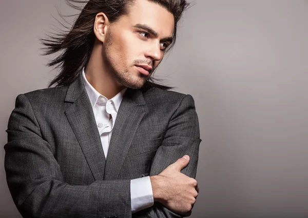 Eleganter junger gutaussehender langhaariger Mann im Kostüm. Modeporträt im Studio. — Stockfoto