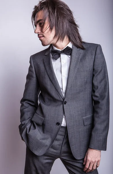 Eleganter junger gutaussehender langhaariger Mann im Kostüm. Modeporträt im Studio. — Stockfoto