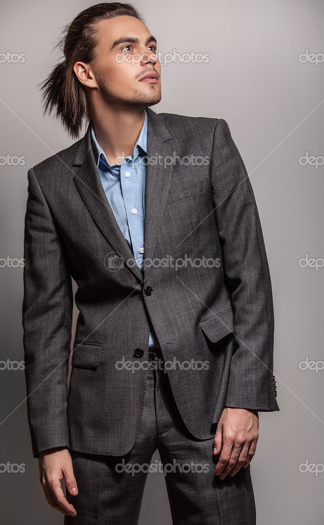 Elegant young handsome long-haired man in costume. Studio fashion ...