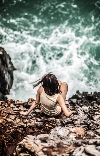 Gyönyörű, fiatal nő ült a sziklán — Stock Fotó