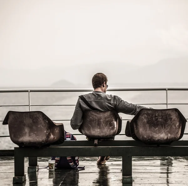 Man sitter vid piren och titta på havet — Stockfoto