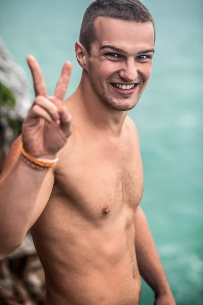 Junger Mann auf Felsen am Meer — Stockfoto