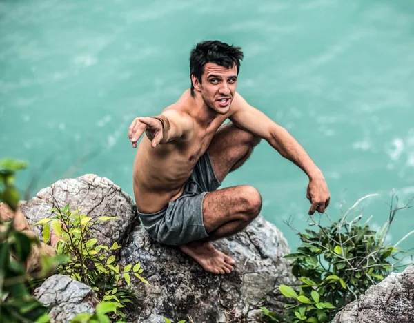Young man on rocks next to the sea — Stock Photo, Image