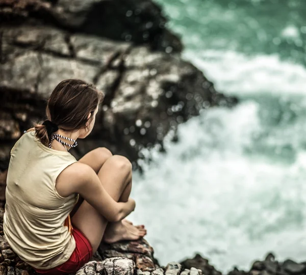 Gyönyörű, fiatal nő ült a sziklán — Stock Fotó