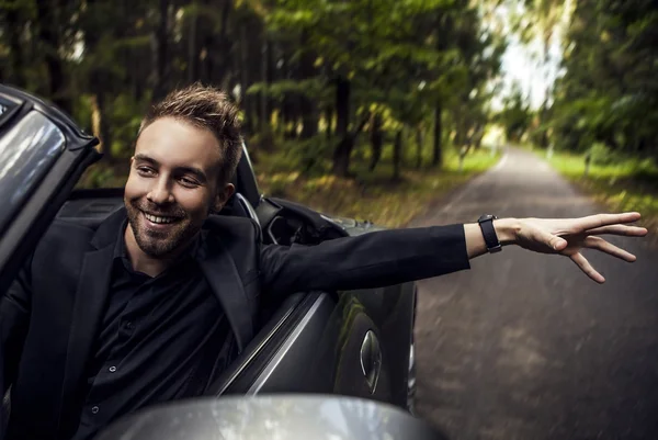 Eleganter junger glücklicher Mann im Cabrio im Freien. — Stockfoto