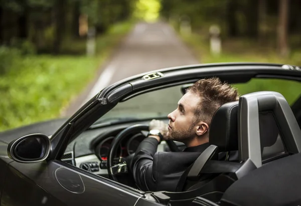 Elegante jonge gelukkig man in converteerbare auto buiten. — Stockfoto