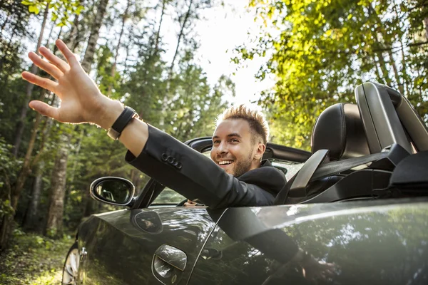 Elegante joven feliz hombre en coche descapotable al aire libre . —  Fotos de Stock