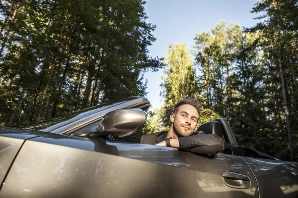 Elegante jovem homem feliz no carro conversível ao ar livre . — Fotografia de Stock