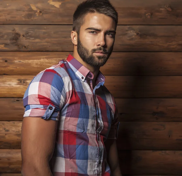 Portrait of young beautiful fashionable man against wooden wall. — Stock Photo, Image