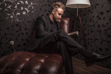 yakışıklı genç iş adamı lüks kanepede rahatlatıcı koyu elbiseli.