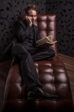 yakışıklı genç iş adamı lüks kanepede rahatlatıcı koyu elbiseli.
