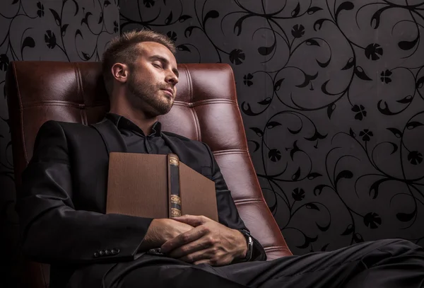 Pohledný mladý obchodní muž v tmavý oblek relaxační na luxusní sofa. — Stock fotografie