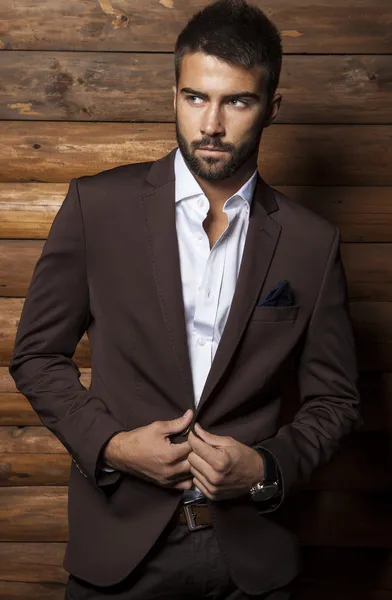 Retrato de jovem belo homem elegante contra a parede de madeira . — Fotografia de Stock