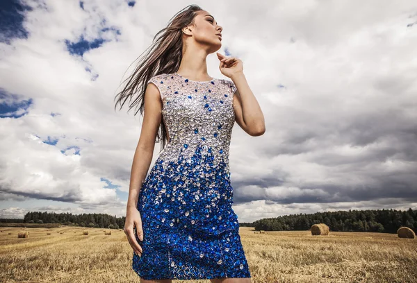 Молода чуттєва і красива жінка в модному біло-блакитному платті позує на полі . — стокове фото