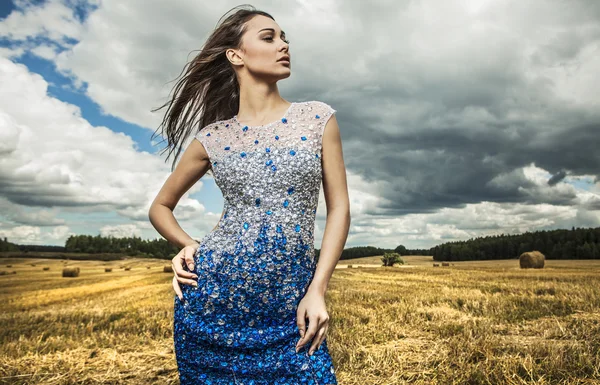 Giovane donna sensuale e di bellezza in un abito alla moda bianco-blu posa sul campo . — Foto Stock