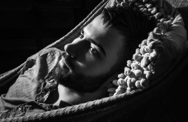 bir hamakta genç yakışıklı ciddi adam portresi. siyah-beyaz yakın çekim fotoğraf.