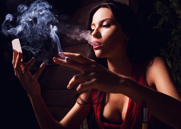 Attraktive junge Frauen schauen in den Spiegel und rauchen Zigarette. — Stockfoto