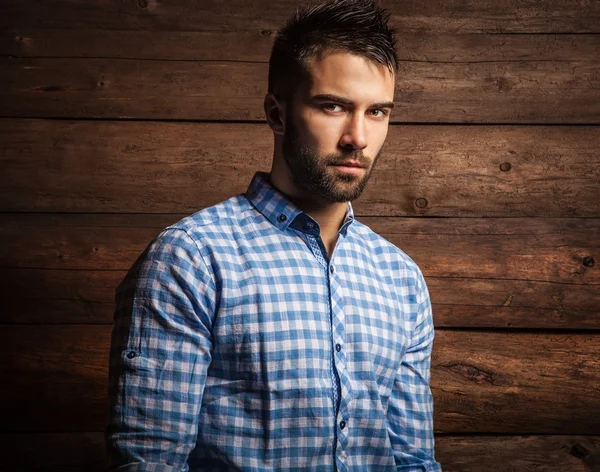 Portrait of young beautiful fashionable man against wooden wall. — Stock Photo, Image