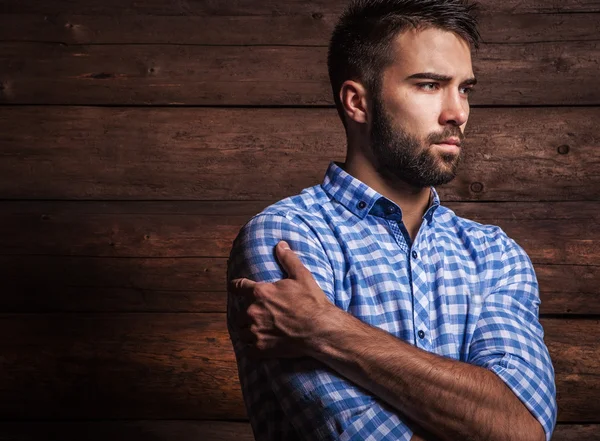 Portrait of young beautiful fashionable man against wooden wall. — Stock Photo, Image
