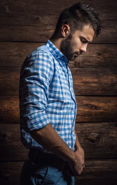 Portrét mladého krásného módního muže proti dřevěné zdi. — Stock fotografie