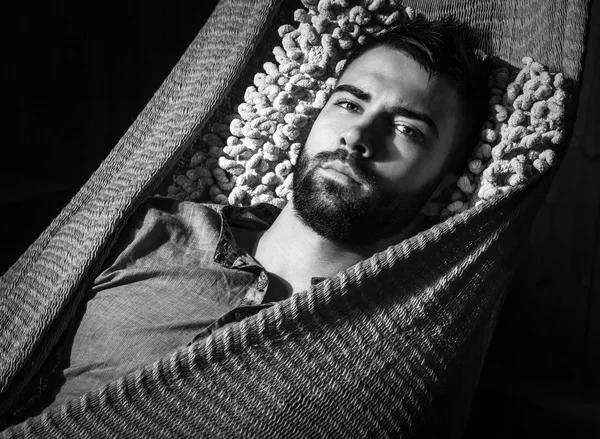 Portrait of young handsome serious man in a hammock. Black-white close-up photo. — Stock Photo, Image