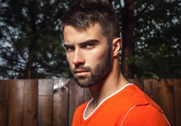 Portrait of young beautiful man in orange, against outdoor background. — Stock Photo, Image