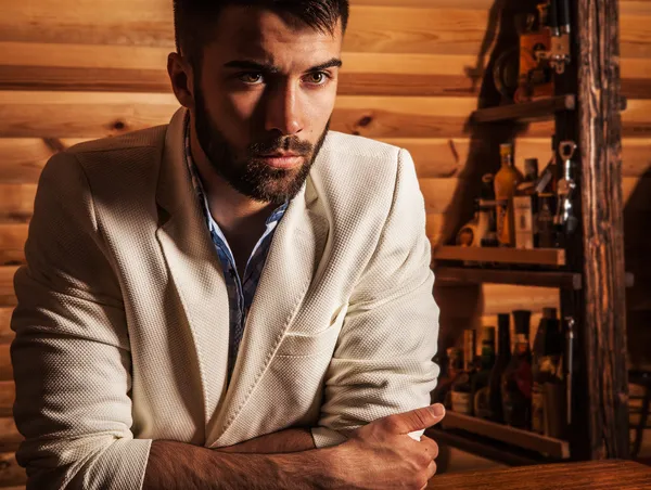 Porträt eines jungen, gut aussehenden Mannes im weißen Anzug in der Nähe der Hausbar. — Stockfoto