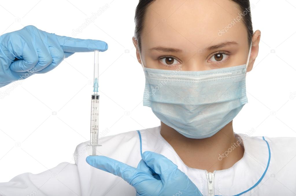 Young nurse in mask and gloves holding a syringe