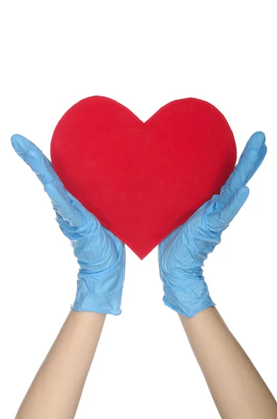 Två händer i medicinska engångshandskar hålla hjärtat — Stockfoto