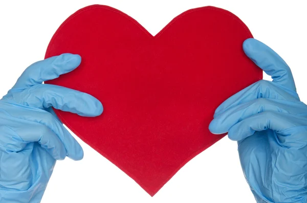 Due mani in guanti medici blu e cuore — Foto Stock