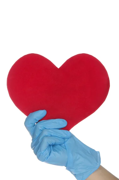 Un brazo con guantes médicos azules mantiene el corazón — Foto de Stock