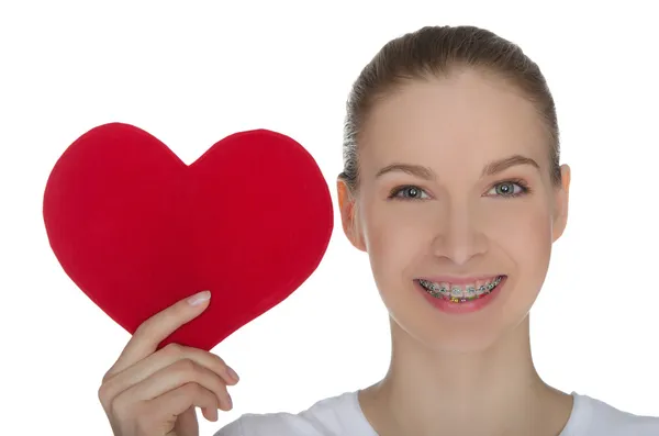 Ragazza felice con bretelle sui denti e cuore rosso — Foto Stock