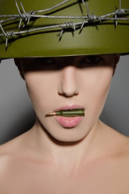 ağzına bir kurşun tutan kask içinde kadın asker