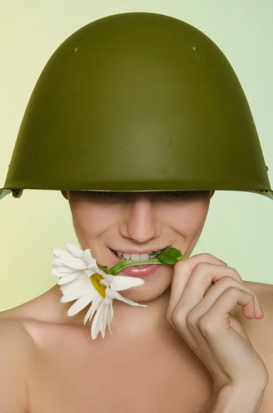 Woman in a military helmet bites chamomile — Stock Photo, Image