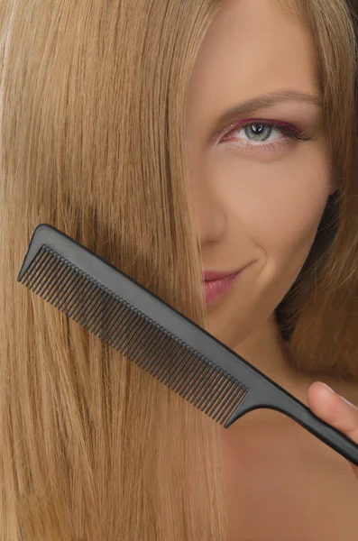 Young woman holding comb straightened hair — Stock Photo, Image