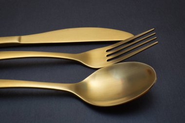 Gold knife, fork and spoon on a black stone background - Food concept photography