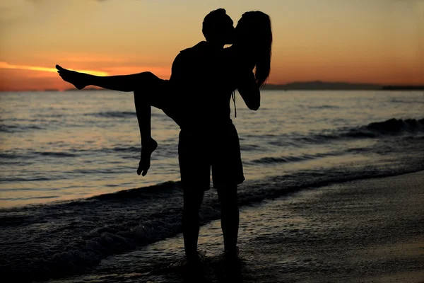 Ett par på stranden vid solnedgången — Stockfoto