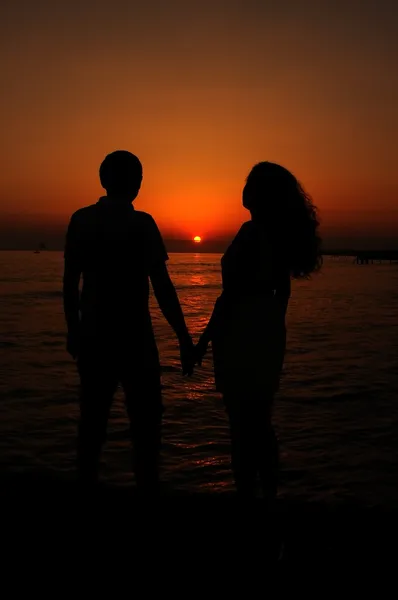 Een paar op het strand bij zonsondergang — Stockfoto