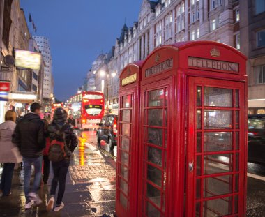 Londra'da gece kalabalık bir caddede kırmızı telefon kulübesi