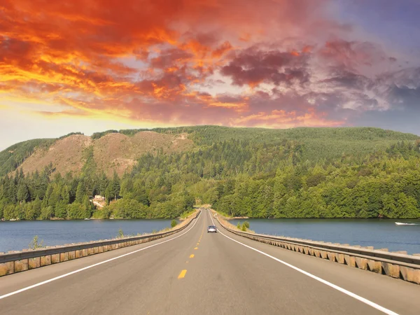 Beautiful road on the lake with sunset colors — Stock Photo, Image