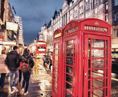 Londra'da gece kalabalık bir caddede kırmızı telefon kulübesi