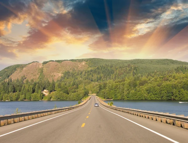 Beautiful road on the lake with sunset colors — Stock Photo, Image