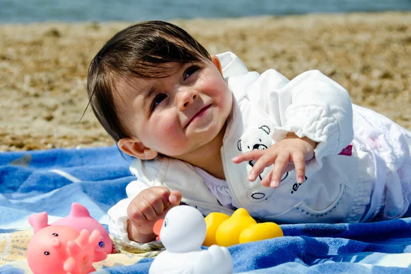 Bebê menina relaxante e jogando em uma toalha de praia — Fotografia de Stock