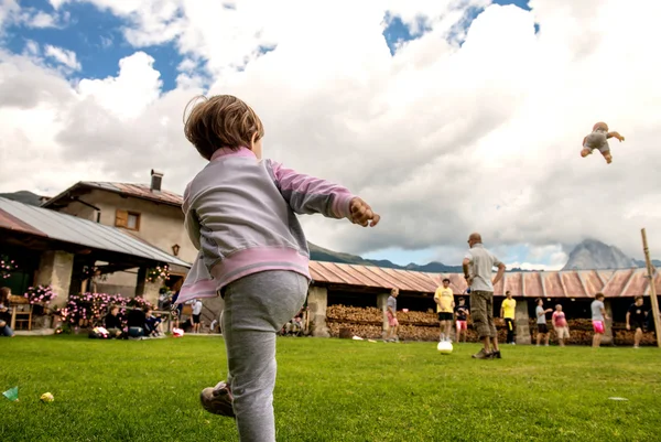Дитина кидає ляльку в повітря в парку на відкритому повітрі — стокове фото
