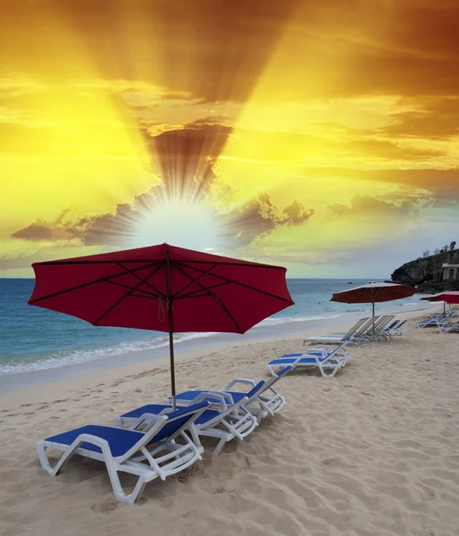 Pouštní pláž se slunečníky a lehátky při západu slunce — Stock fotografie